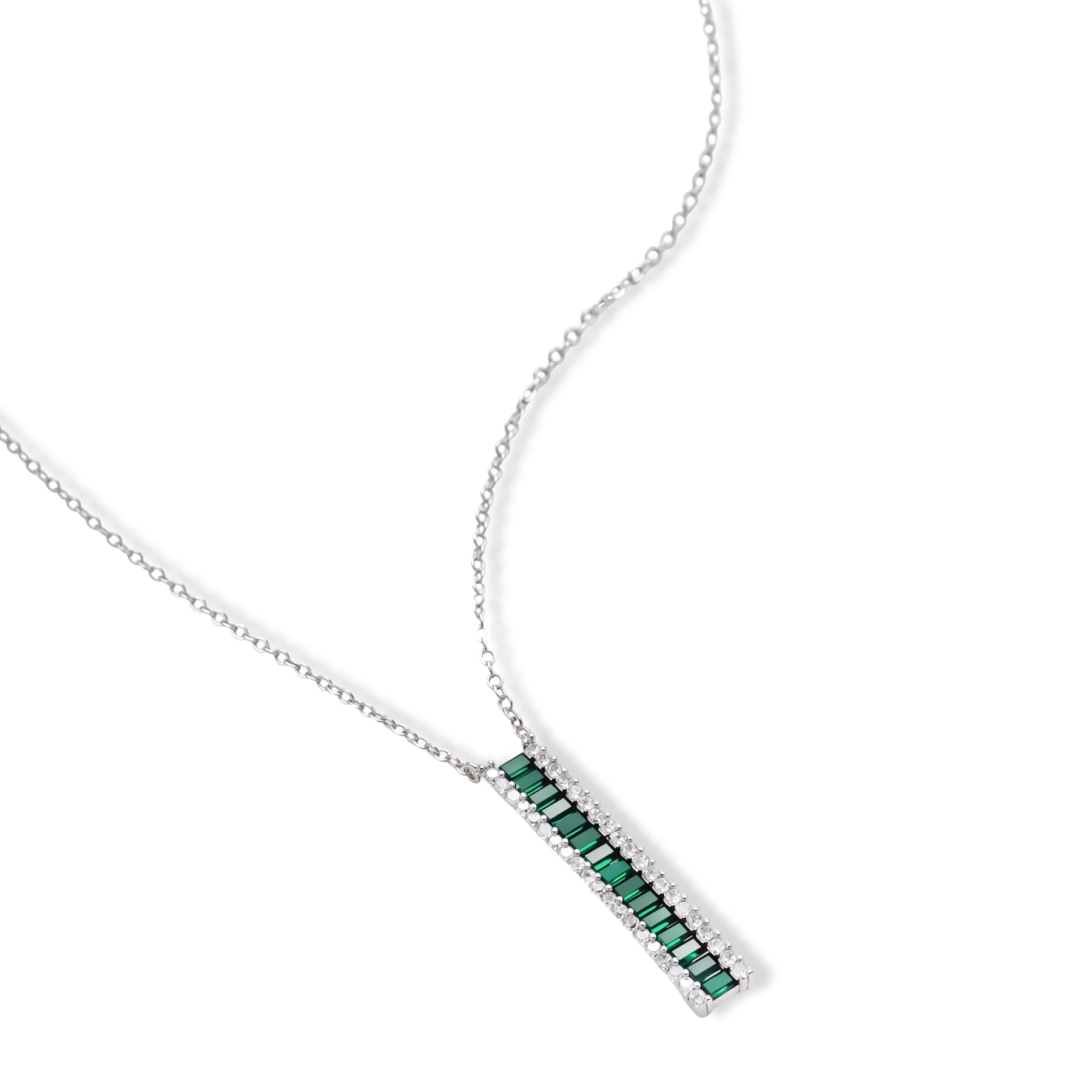 White gold plated jewelry set with emerald green rectangular stones and clear crystals in geometric rows on white background.