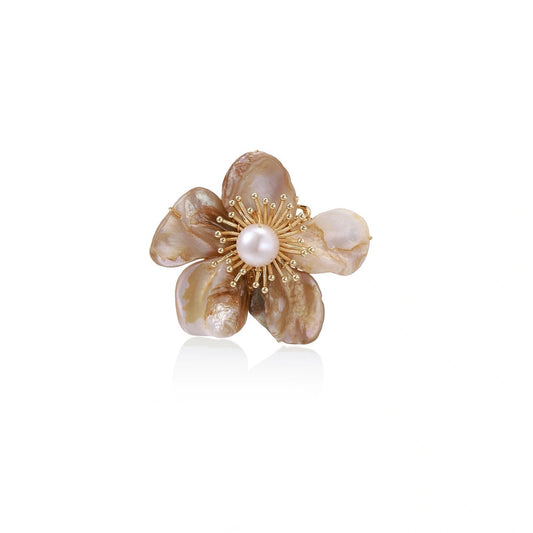 Flower-shaped brooch with iridescent shell petals, freshwater pearl center, and gold-plated radiating details.