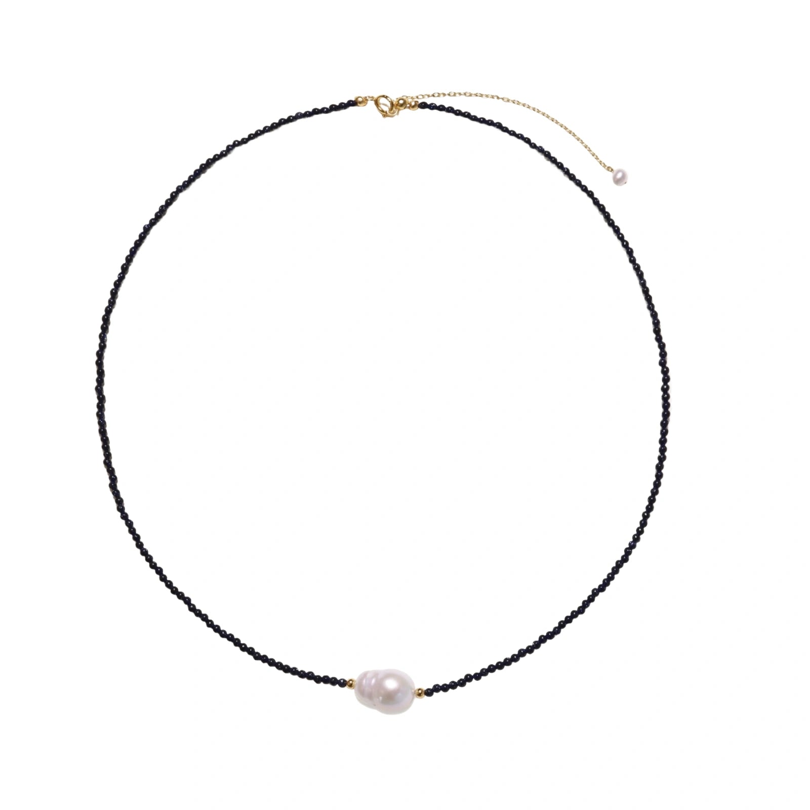 Delicate necklace with black blue sandstone beads and baroque pearl center on white background with gold accents.