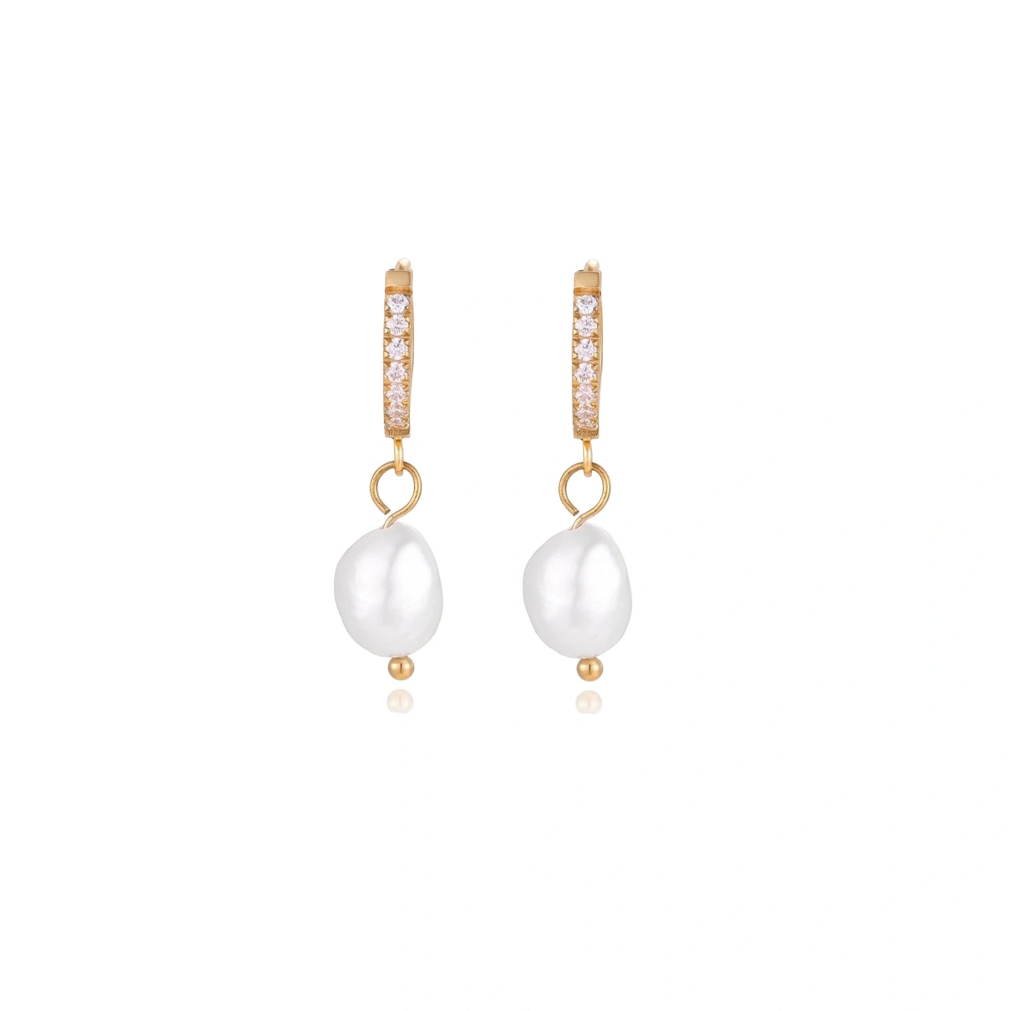 Gold huggie hoop earrings with pavé crystals and white freshwater pearl drops on cream background