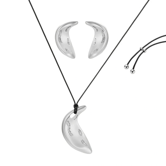 Crescent moon shaped pendant and earrings in eco-zinc alloy with curved crystal inlay patterns on light background.