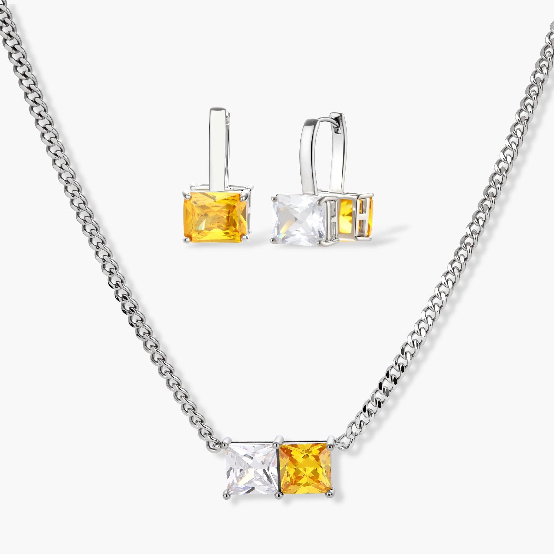 Silver curb-chain necklace and hoop drop earrings set with paired yellow and clear square zirconia stones.