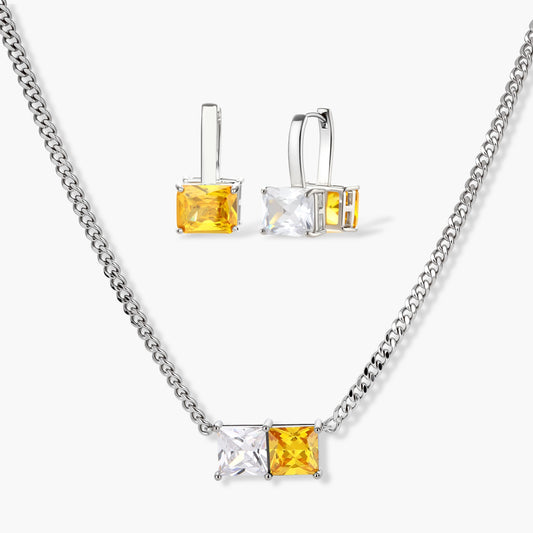 Silver curb-chain necklace and hoop drop earrings set with paired yellow and clear square zirconia stones.