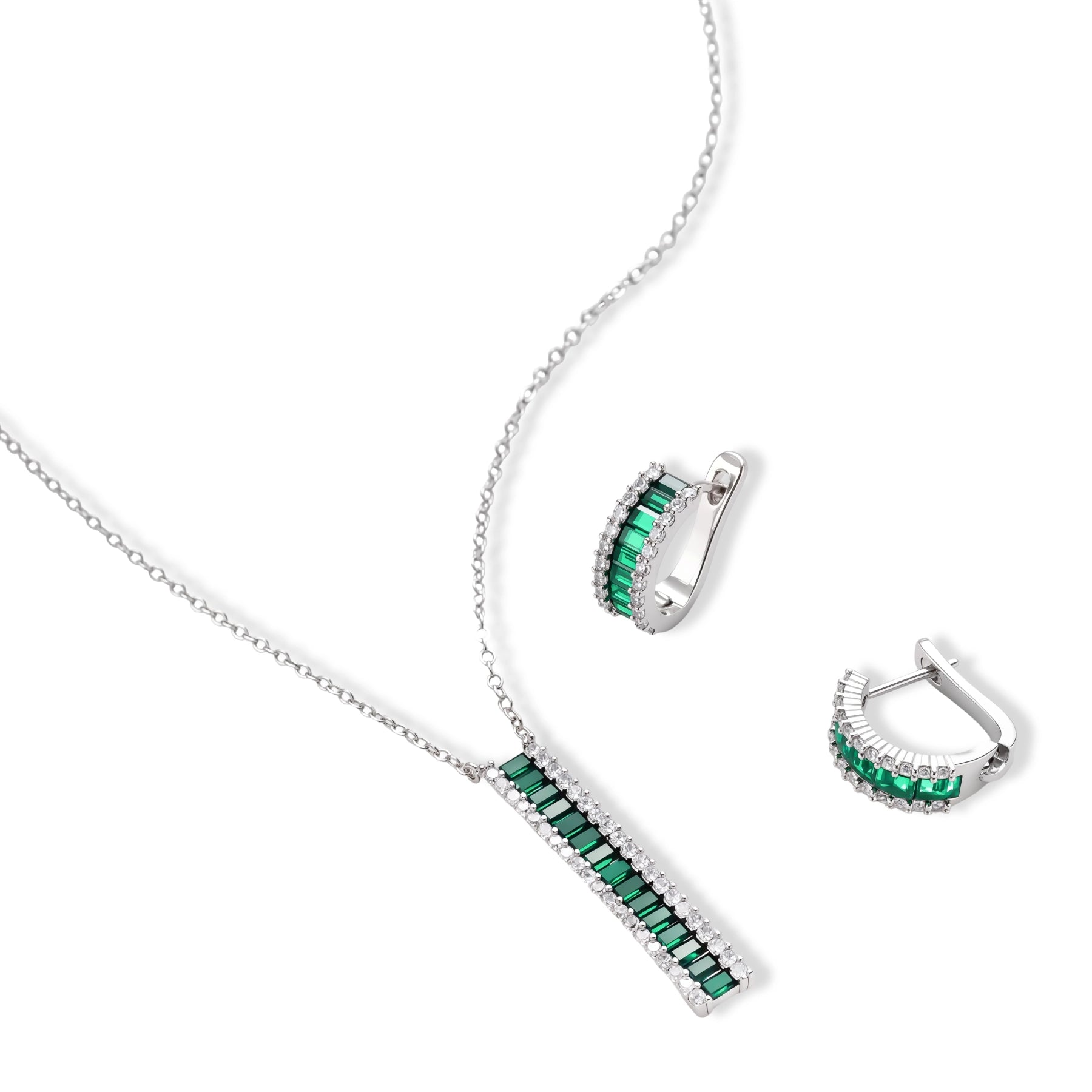 White gold plated jewelry set with emerald green rectangular stones and clear crystals in geometric rows on white background.
